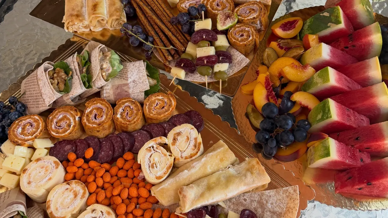 Catering sto sa slanim platama, rolatima i voćem, postavljen na terasi